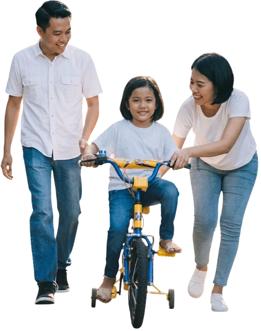 Home Smiling family helping a young child ride a bicycle